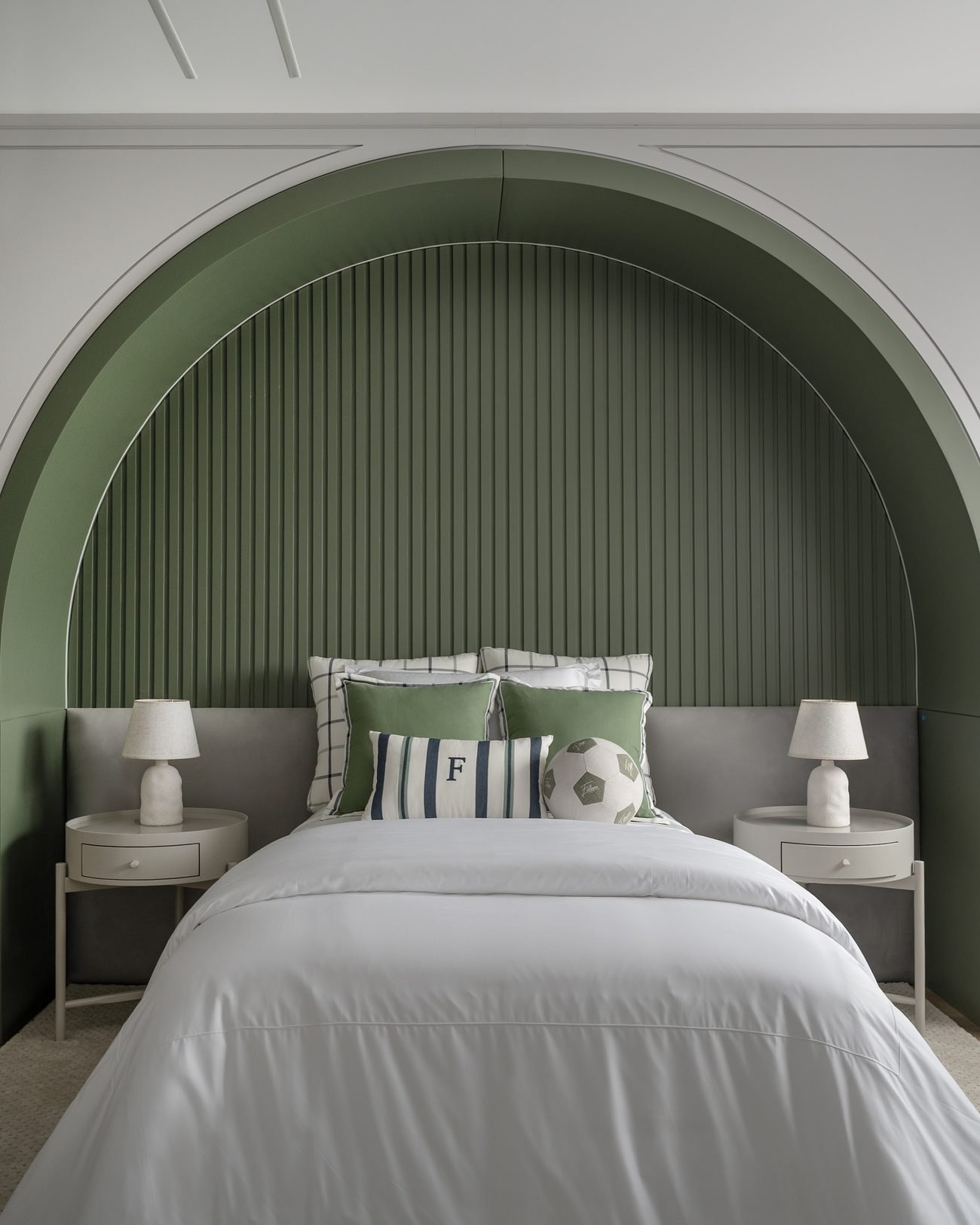 Quarto com arco canelado em verde sobre a cabeceira