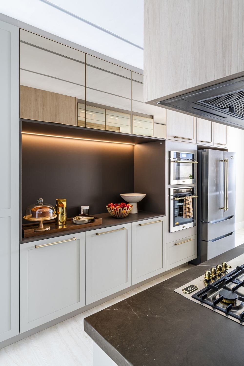 Cozinha com cooktop, forno embutido e bancada em pedra escura