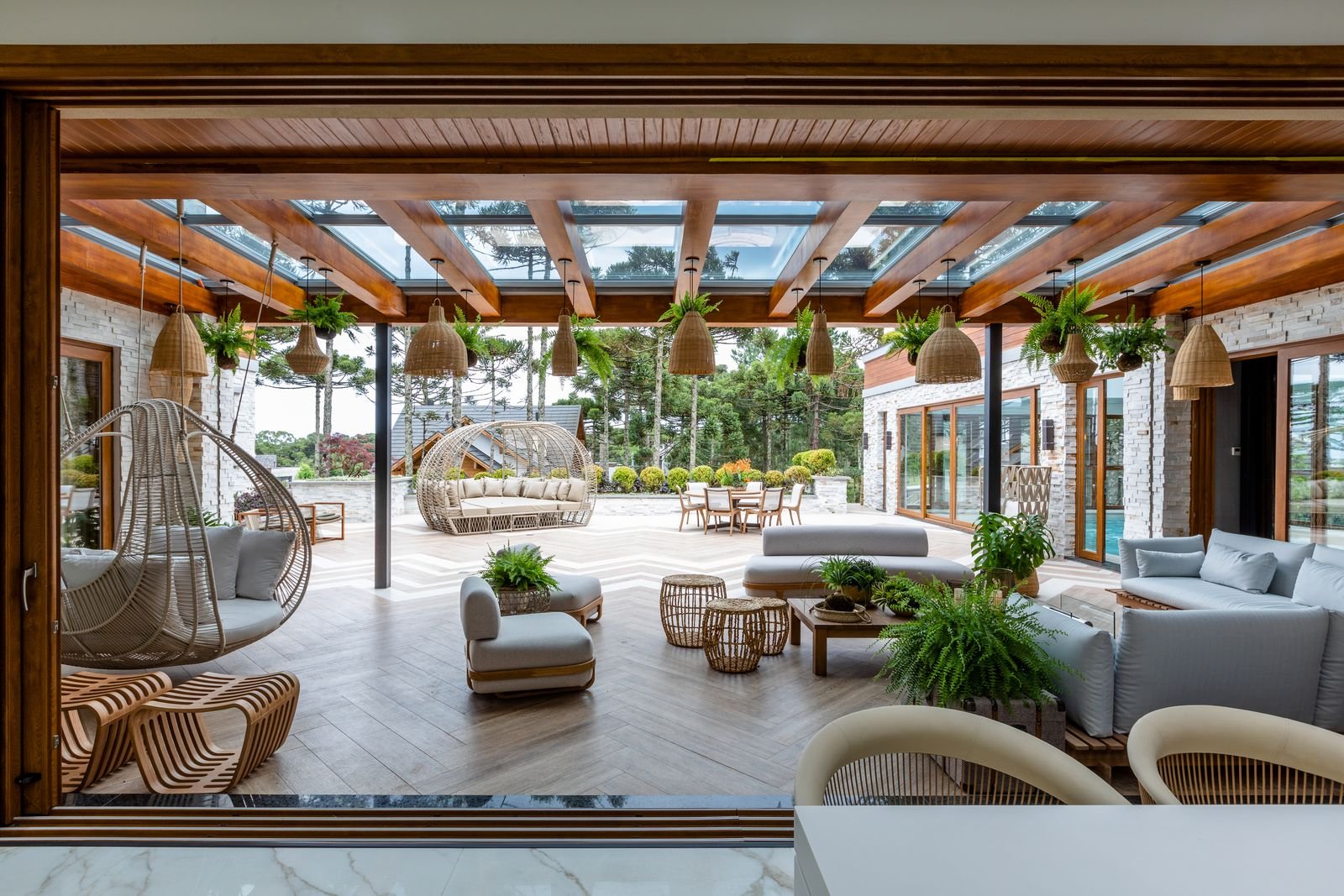 Varanda gourmet com pergolado de madeira e mobiliário em fibra natural